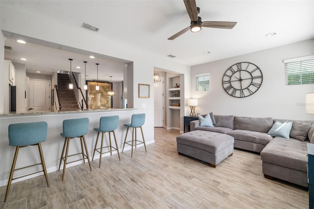 living room with light wood-style floors, a ceiling fan, plenty of natural light, baseboards, and recessed lighting
