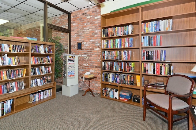 4420 Exeter Dr Unit L104, Longboat Key, FL 34228 - sitting room featuring brick wall, wall of books, and carpet flooring