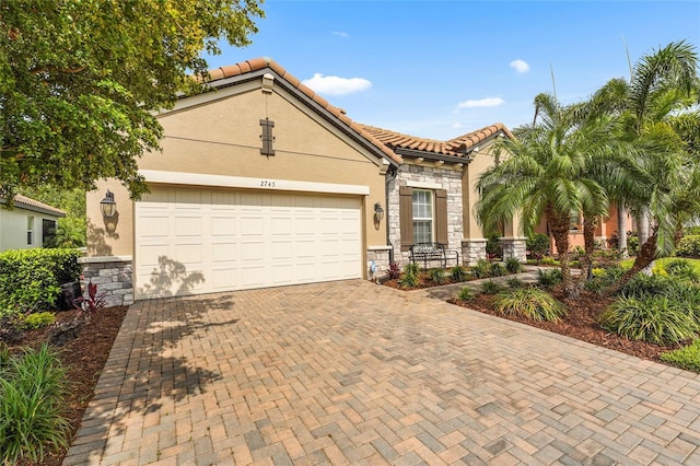 2745 62nd Ave E, Ellenton, FL 34222 - mediterranean / spanish house with stone siding, decorative driveway, stucco siding, and a garage