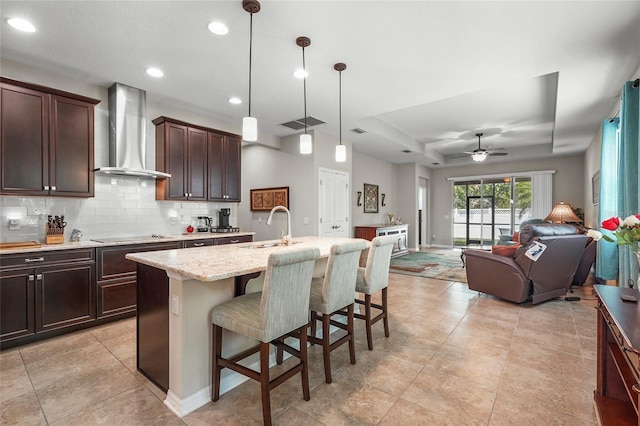 2745 62nd Ave E, Ellenton, FL 34222 - kitchen featuring wall chimney exhaust hood, a sink, tasteful backsplash, a tray ceiling, and a kitchen bar
