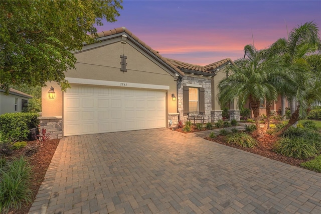 2745 62nd Ave E, Ellenton, FL 34222 - view of front of house with stone siding, decorative driveway, stucco siding, an attached garage, and a tile roof