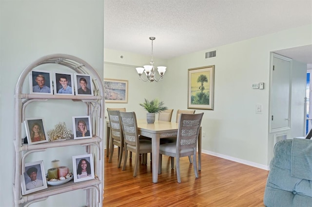 7301 29th Avenue Dr W Unit 108, Bradenton, FL 34209 - dining room with light wood finished floors, a chandelier, baseboards, and a textured ceiling
