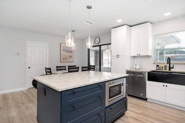 3303 32nd St W, Bradenton, FL 34205 - kitchen featuring appliances with stainless steel finishes, white cabinets, light wood finished floors, light stone counters, and recessed lighting