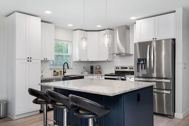 3303 32nd St W, Bradenton, FL 34205 - kitchen with appliances with stainless steel finishes, wall chimney range hood, light wood-style floors, a sink, and a kitchen island