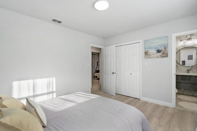 3303 32nd St W, Bradenton, FL 34205 - bedroom with light wood-style floors, a closet, baseboards, ensuite bathroom, and a sink
