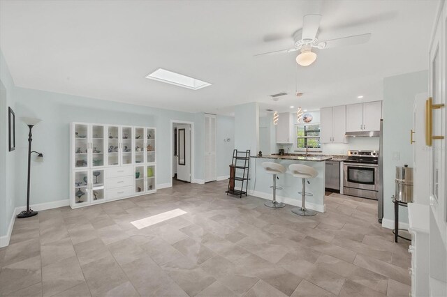 3500 Green View Ct Unit 45, Sarasota, FL 34231 - kitchen with stainless steel range oven, a kitchen breakfast bar, under cabinet range hood, open floor plan, and a skylight