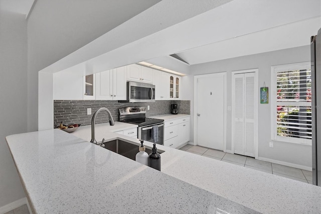 4079 Woodview Dr, Sarasota, FL 34232 - kitchen with stainless steel appliances, glass insert cabinets, decorative backsplash, and light stone counters