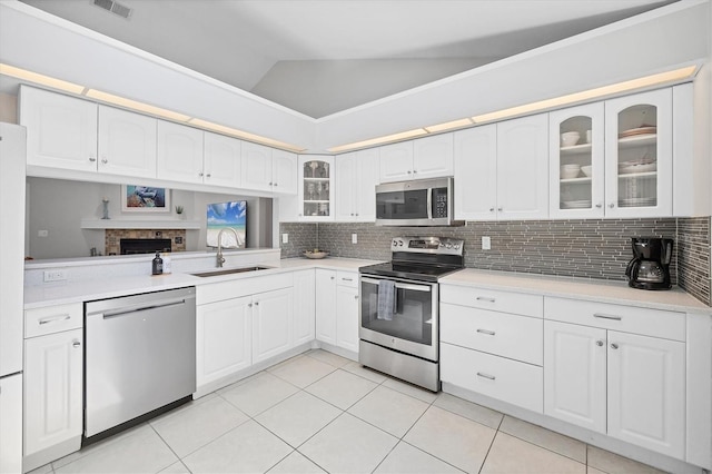 4079 Woodview Dr, Sarasota, FL 34232 - kitchen with appliances with stainless steel finishes, a sink, glass insert cabinets, light tile patterned floors, and decorative backsplash