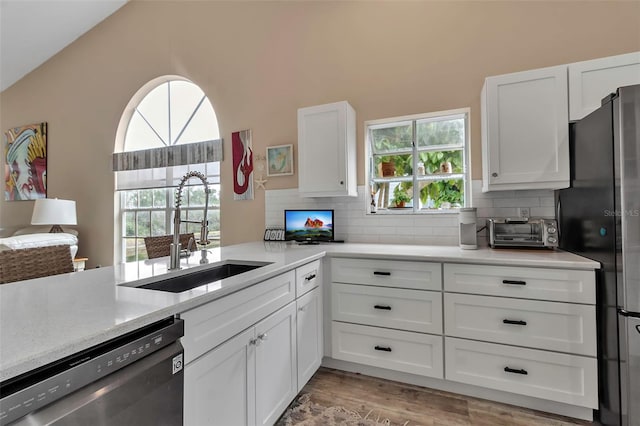 1322 Perico Point Cir, Bradenton, FL 34209 - kitchen featuring stainless steel dishwasher, a sink, freestanding refrigerator, backsplash, and white cabinets