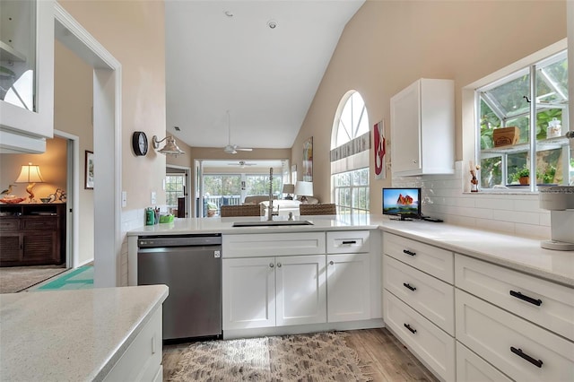 1322 Perico Point Cir, Bradenton, FL 34209 - kitchen with stainless steel dishwasher, high vaulted ceiling, white cabinets, light wood finished floors, and tasteful backsplash