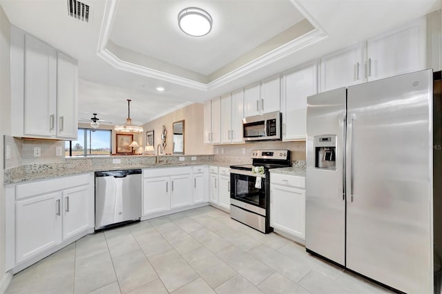 kitchen with stainless steel appliances, a raised ceiling, white cabinetry, light stone counters, and tasteful backsplash