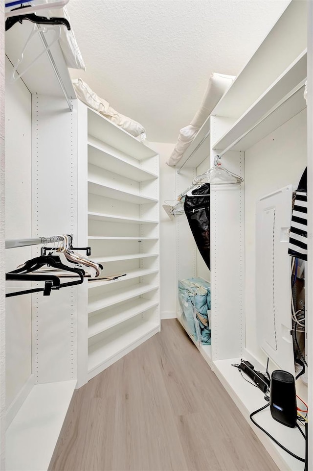 walk in closet with light wood-style flooring
