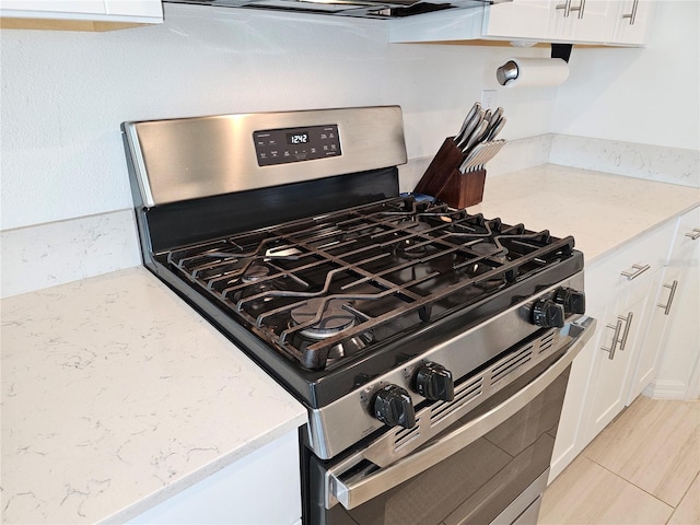 13156 Merlot Sunstone Cv, Parrish, FL 34219 - kitchen view of gas range, white cabinetry, and light stone counters