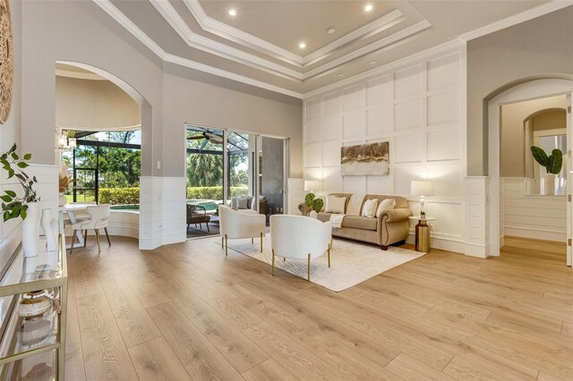 52 Grande Fairway, Englewood, FL 34223 - living area with a decorative wall, arched walkways, light wood finished floors, a tray ceiling, and wainscoting
