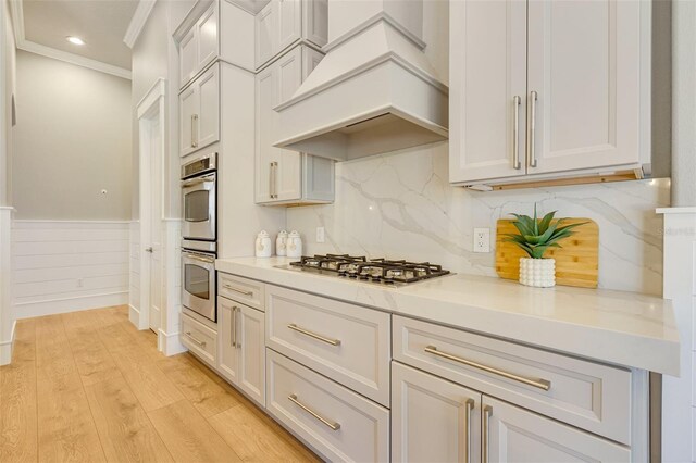 52 Grande Fairway, Englewood, FL 34223 - kitchen with premium range hood, appliances with stainless steel finishes, light countertops, wainscoting, and light wood-style floors