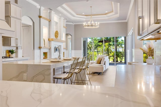 52 Grande Fairway, Englewood, FL 34223 - kitchen featuring arched walkways, a towering ceiling, a chandelier, crown molding, and light stone counters