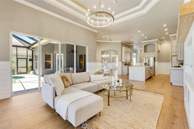 52 Grande Fairway, Englewood, FL 34223 - living room with a chandelier, ornamental molding, light wood finished floors, a tray ceiling, and wainscoting