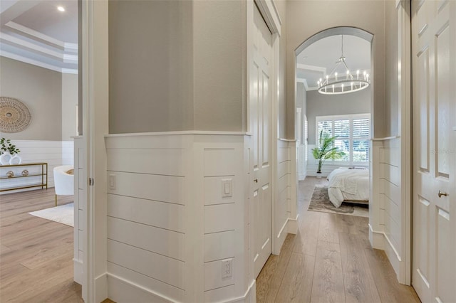 52 Grande Fairway, Englewood, FL 34223 - corridor with wainscoting, light wood finished floors, a decorative wall, arched walkways, and a chandelier