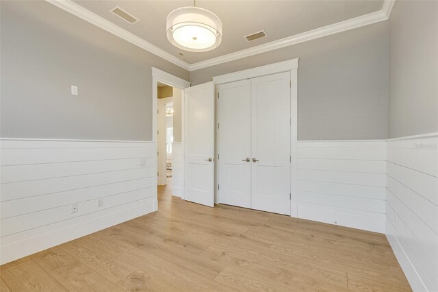 52 Grande Fairway, Englewood, FL 34223 - unfurnished bedroom with ornamental molding, light wood-style floors, a wainscoted wall, and a closet