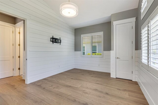 52 Grande Fairway, Englewood, FL 34223 - unfurnished room with vaulted ceiling, plenty of natural light, light wood-style floors, wood walls, and wainscoting