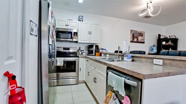 2330 28th Ave E, Palmetto, FL 34221 - kitchen with appliances with stainless steel finishes, a peninsula, a sink, light tile patterned floors, and white cabinets