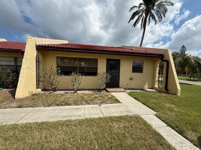 1304 56th St W Unit 1304, Bradenton, FL 34209 - view of front of house with stucco siding, a front yard, and a tile roof