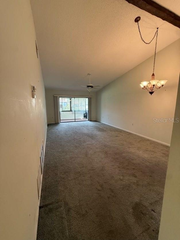 1304 56th St W Unit 1304, Bradenton, FL 34209 - spare room featuring carpet flooring, vaulted ceiling, a chandelier, and a textured ceiling