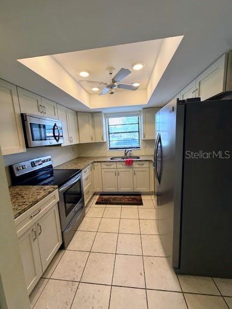 1304 56th St W Unit 1304, Bradenton, FL 34209 - kitchen with stainless steel appliances, a raised ceiling, a sink, light tile patterned floors, and a ceiling fan
