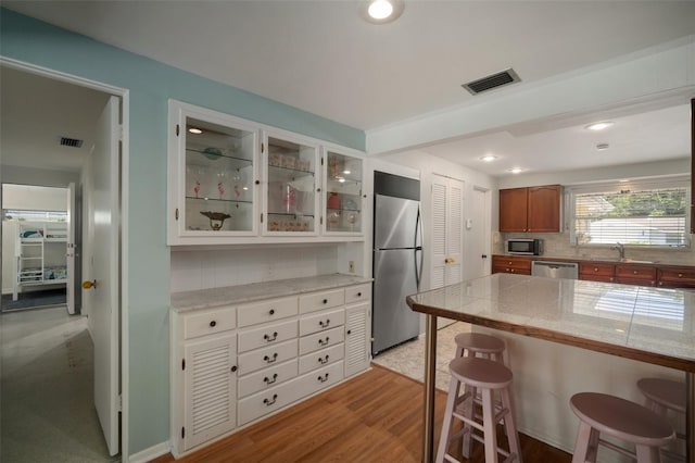 7202 18th Ave NW, Bradenton, FL 34209 - kitchen featuring stainless steel appliances, a breakfast bar area, glass insert cabinets, decorative backsplash, and tile countertops