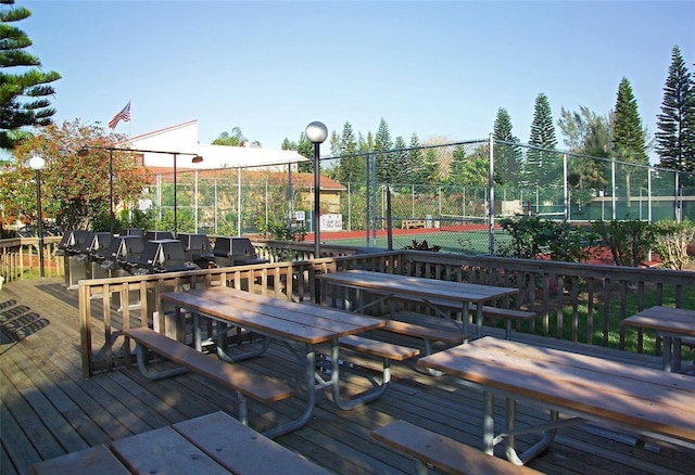4621 Gulf Of Mexico Dr Unit 2F, Longboat Key, FL 34228 - wooden deck featuring outdoor dining area, fence, and a tennis court