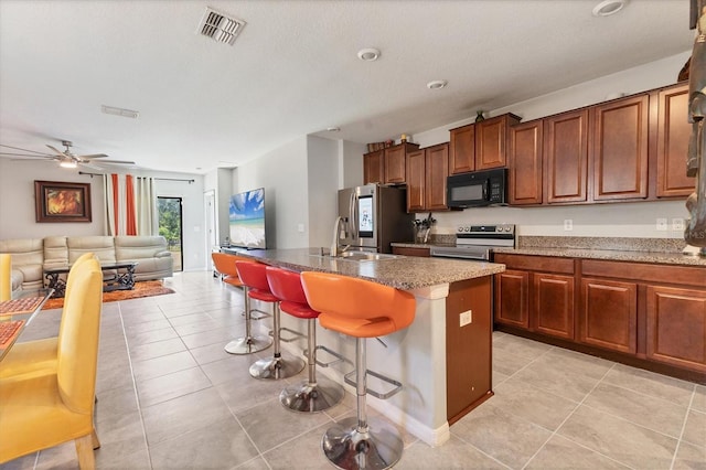 5033 Brickwood Rise Dr, Wimauma, FL 33598 - kitchen with stainless steel appliances, a sink, a kitchen breakfast bar, a center island with sink, and light tile patterned floors