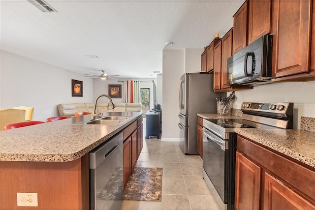 5033 Brickwood Rise Dr, Wimauma, FL 33598 - kitchen featuring appliances with stainless steel finishes, a sink, light tile patterned flooring, ceiling fan, and an island with sink