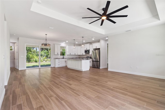 2704 Gaspar Ave, North Port, FL 34288 - unfurnished living room with a raised ceiling, a ceiling fan, baseboards, recessed lighting, and light wood-style floors
