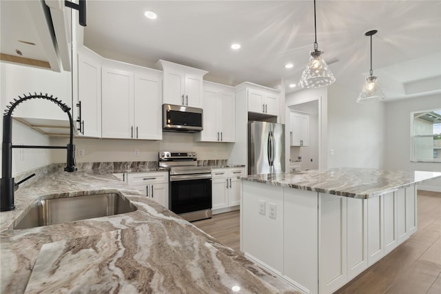 2704 Gaspar Ave, North Port, FL 34288 - kitchen with stainless steel appliances, a sink, light wood-type flooring, a center island, and white cabinets