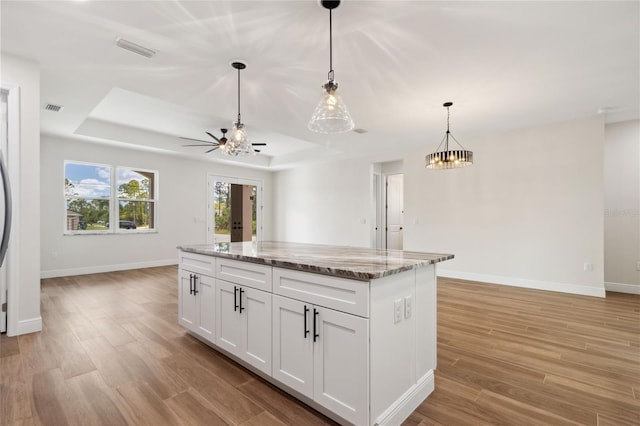 2704 Gaspar Ave, North Port, FL 34288 - kitchen with a tray ceiling, open floor plan, baseboards, white cabinetry, and light wood-style flooring