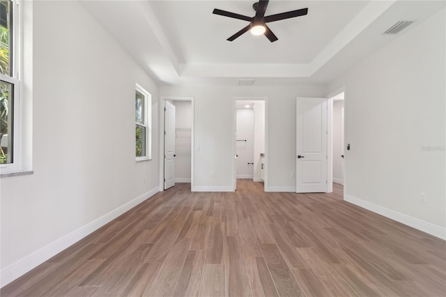 2704 Gaspar Ave, North Port, FL 34288 - unfurnished bedroom featuring a tray ceiling, light wood-type flooring, a walk in closet, baseboards, and ensuite bathroom