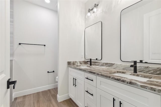 2704 Gaspar Ave, North Port, FL 34288 - full bathroom featuring baseboards, toilet, wood finished floors, and double vanity