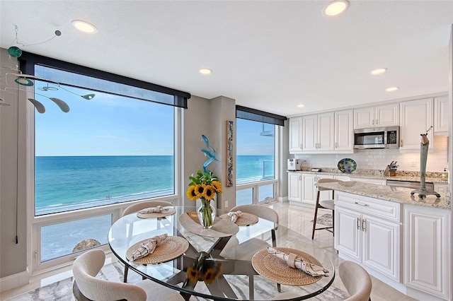 dining area with recessed lighting, a water view, baseboards, and light marble finish floors