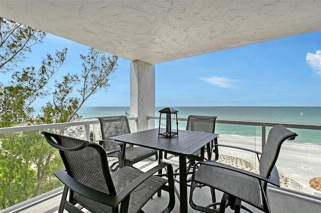 balcony featuring view of water and beach and outdoor dining space
