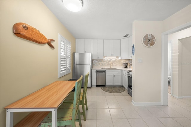2037AND2039 Jo An Dr, Sarasota, FL 34231 - kitchen with appliances with stainless steel finishes, white cabinetry, light countertops, decorative backsplash, and light tile patterned floors