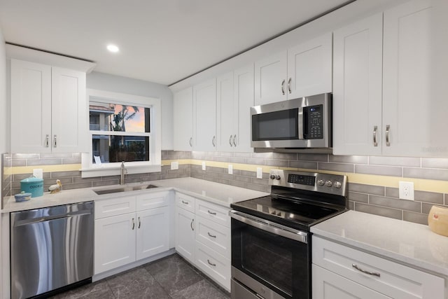 kitchen featuring stainless steel appliances, a sink, white cabinetry, decorative backsplash, and light stone countertops