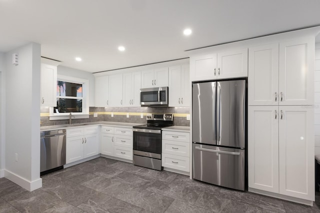 kitchen with appliances with stainless steel finishes, a sink, white cabinets, backsplash, and recessed lighting