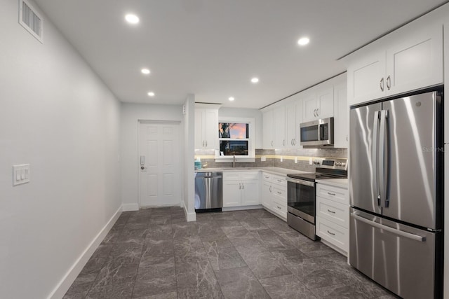 kitchen featuring appliances with stainless steel finishes, baseboards, white cabinets, decorative backsplash, and recessed lighting