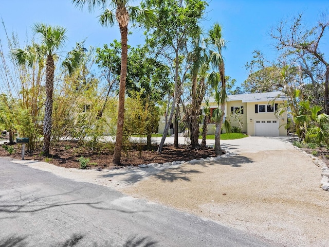 7320 Melaleuca Way, Siesta Key, FL 34242 - view of front facade with dirt driveway, a garage, and stucco siding