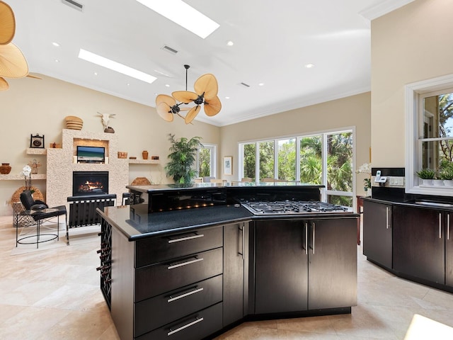 7320 Melaleuca Way, Siesta Key, FL 34242 - kitchen with gas cooktop, a skylight, dark countertops, a warm lit fireplace, and vaulted ceiling