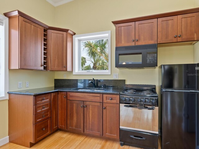 7320 Melaleuca Way, Siesta Key, FL 34242 - kitchen featuring black appliances, a sink, ornamental molding, dark stone countertops, and light wood finished floors