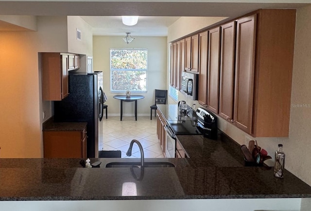7911 Grand Estuary Trl Unit 201, Bradenton, FL 34212 - kitchen with stainless steel appliances, light tile patterned floors, brown cabinets, and dark stone counters
