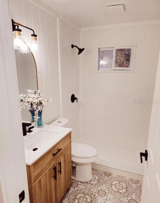 16079 SE Janet St, Blountstown, FL 32424 - bathroom featuring a shower, vanity, tile patterned floors, toilet, and ornamental molding