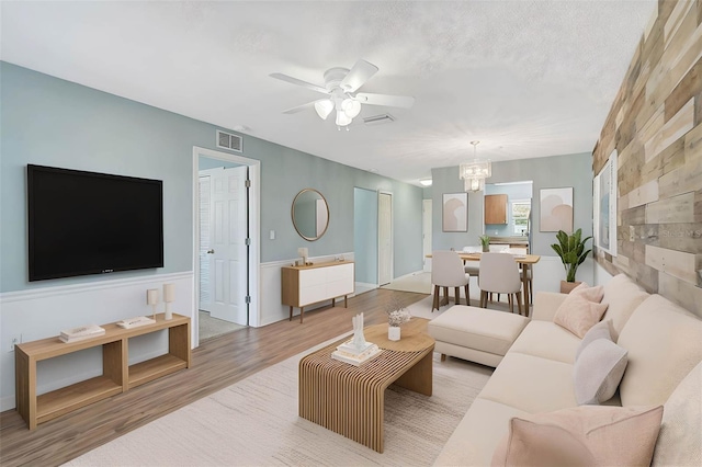 602 Park Cir, Bradenton, FL 34207 - living area featuring wood finished floors, a ceiling fan, a chandelier, and a wainscoted wall