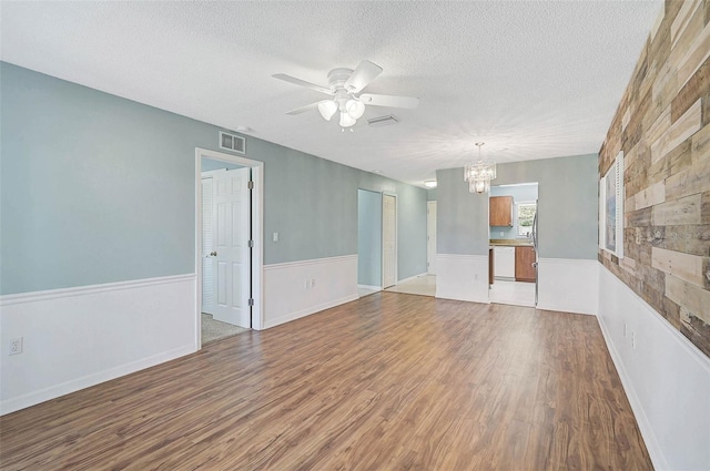 602 Park Cir, Bradenton, FL 34207 - spare room featuring a chandelier, ceiling fan, light wood-type flooring, a textured ceiling, and wainscoting